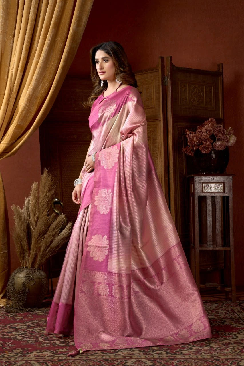 Woman wearing a pink saree with a matching blouse in a warm-toned room.
